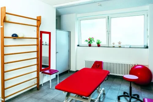 Weiterer heller Behandlungsraum mit roter Liege